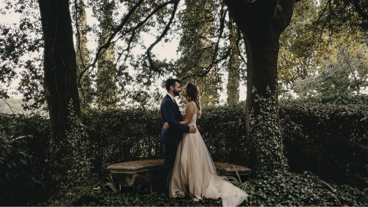 La coppia di sposi si abbracciano tra gli alberi del giardino segreto di Villa Dianella.